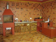 an old fashioned kitchen with red brick walls and floor tiles on the wall, wood cabinets in the middle