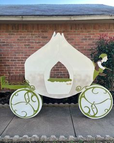 a paper horse drawn carriage sitting in front of a brick building with green trimmings