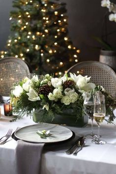 the table is set with white flowers and greenery for an elegant christmas dinner setting