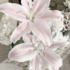 a vase filled with white flowers on top of a wooden table next to a mirror