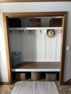 a mudroom with baskets and hats on the shelves, next to a rug in front of it