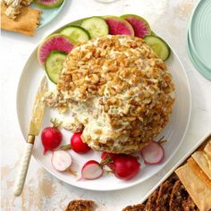 a white plate topped with food next to sliced radishes and crackers on top of a table