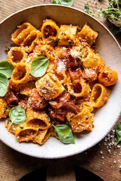 pasta with tomato sauce and basil leaves in a white bowl on a wooden table top