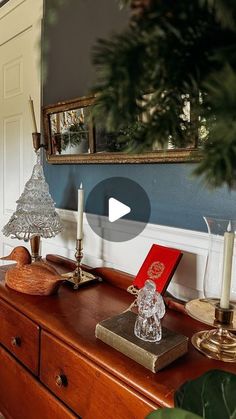 a wooden dresser topped with a christmas tree next to a mirror and candlesticks