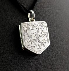 "This beautiful antique Victorian sterling silver locket pendant is so decorative and unique with its attractive nature inspired design. It is engraved to the front in the aesthetic manner with leaves and the locket is a lovely shield shape.  It has a silver jump ring and space internally for two pictures or tiny mementos but there are no glazed covers.  The locket has a smooth reverse and is marked with a makers mark.  This is perfect for adding to your favourite long chain or necklace.  Marks and era: Victorian era, marked JR, tests as sterling silver, c1880s Condition: Good used condition overall, some age commensurate wear and signs of use, light surface wear.  Approx measurements: 0.75\" width  1\" height including the bale.  Weighs approx 7.85 grams Any questions or queries please co Antique Sterling Silver Etched Locket Necklace, Antique Engraved Locket Necklace With Flower Pendant, Antique Etched Sterling Silver Locket Necklace, Antique Engraved Flower Pendant Locket Necklace, Antique Silver Engraved Flower Pendant Jewelry, Carved Silver Medallion Jewelry, Sterling Silver Locket Necklace With Flower Pendant, Sterling Silver Flower Pendant Locket Necklace, Silver Etched Medallion Locket Necklace