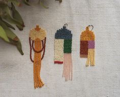 three beaded earrings sitting on top of a table next to a potted plant