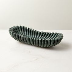 a green bowl sitting on top of a white table