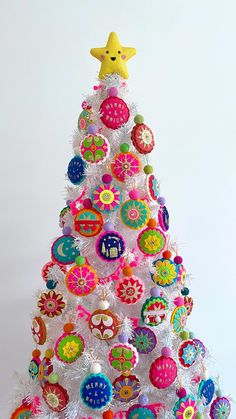 a brightly colored christmas tree with ornaments on it's sides and a star above the top