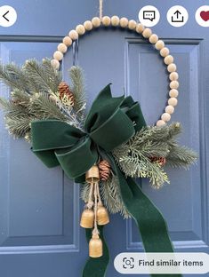 a wreath with bells and pine cones hanging on a blue front door decorated for christmas