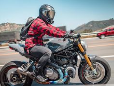 a man riding on the back of a motorcycle down a highway