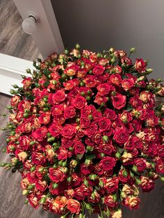 a large bouquet of red roses on the floor next to a doorway with a white door in the background