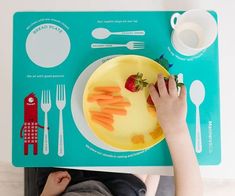 a child is sitting at a table with a plate of food and utensils