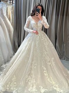 a woman in a wedding dress taking a selfie with her cell phone while looking at it