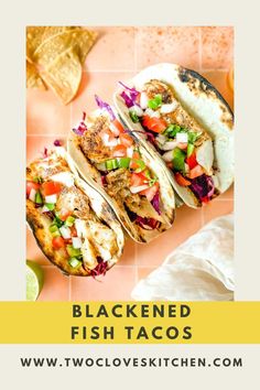 three fish tacos on a cutting board with limes and cilantro in the background