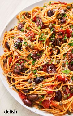 a white plate topped with spaghetti and olives