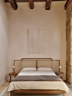 a large bed in a bedroom next to a wall with exposed wood beams and a painting on the wall