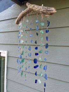 a wind chime hanging on the side of a house with blue and green glass beads