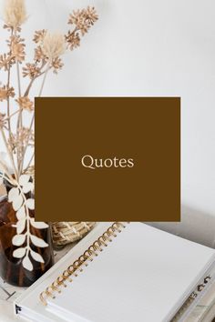 an open notebook sitting on top of a table next to a vase with dried flowers