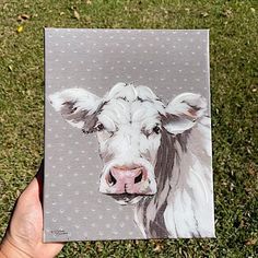 a painting of a cow is being held in the grass