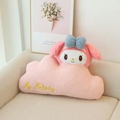 a pink stuffed animal sitting on top of a white couch next to a framed picture