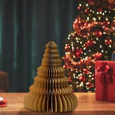 a christmas tree made out of folded paper next to a gift box and candle holder