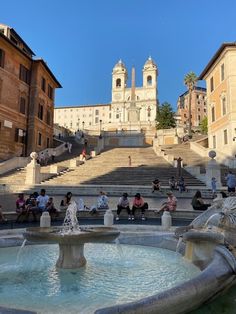 several people sitting on steps near a fountain