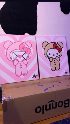 two hello kitty paintings sitting on top of a cardboard box