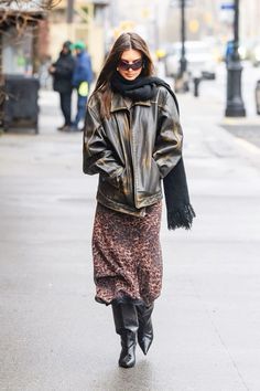 a woman walking down the street wearing a leather jacket