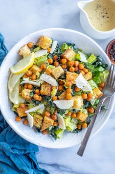 a white bowl filled with lettuce, chickpeas and croutons