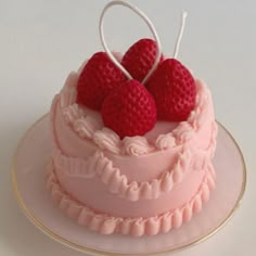 a pink cake with three raspberries on top