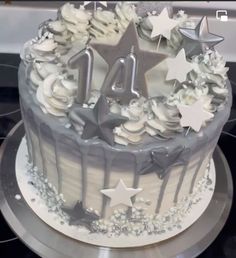 a birthday cake with white frosting and stars on the top is decorated with silver icing