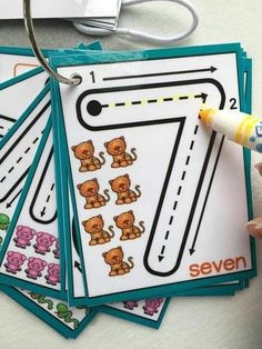 a hand holding a marker next to some stickers with animals on them and the number seven