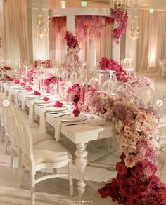 a long table with white chairs and pink flowers on the top is set for a formal dinner