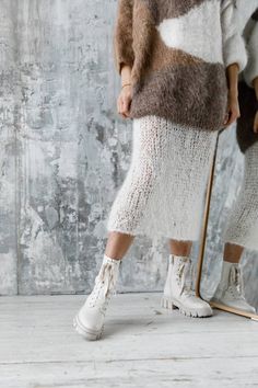 a woman standing in front of a mirror wearing white boots and a fuzzy knit sweater