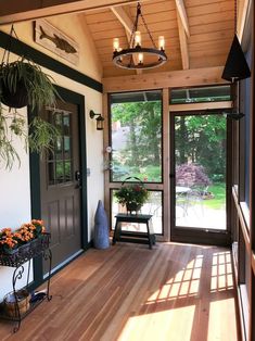 the sun shines through the glass doors onto an enclosed porch with potted plants