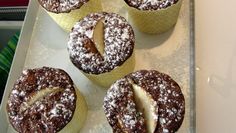 several pastries are sitting on a tray with powdered sugar and chocolate icing