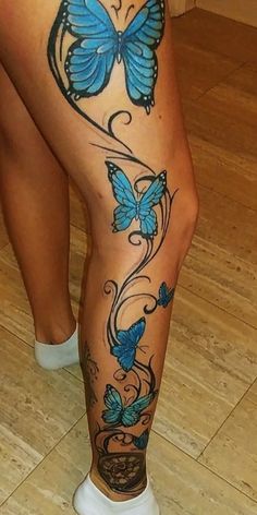 a woman's legs with blue butterflies and swirls on the bottom part of her leg