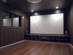 an empty room with speakers and a large screen on the wall in front of it