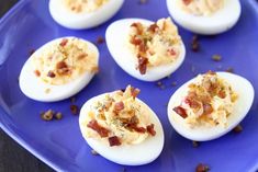 deviled eggs with bacon and cheese are on a blue plate, ready to be eaten