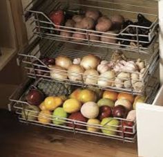 two metal baskets filled with fruits and vegetables on top of an oven door drawer in a kitchen