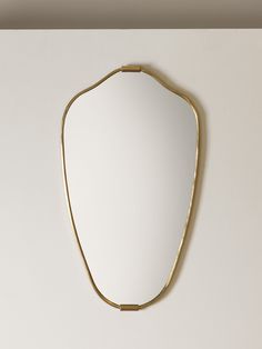 a mirror hanging on the wall with a gold frame and metal bar at the bottom