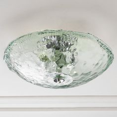 a glass bowl hanging from the ceiling in front of a white wall and window sill