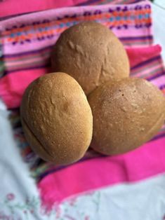 three round bread rolls sitting on top of a pink and white towel next to each other