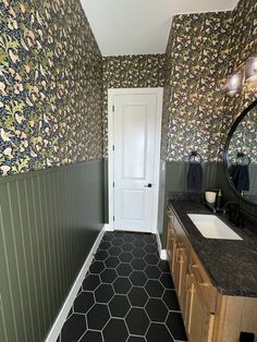 a bathroom with black and white tile flooring next to a sink under a mirror