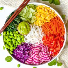 a bowl filled with vegetables and chopsticks on top of a table