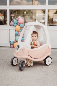 a baby in a pink and white toy car