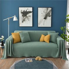 a living room with two paintings on the wall and a couch covered in yellow covers