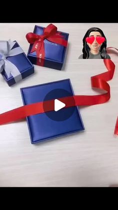 a woman wearing red sunglasses is opening a blue gift box with a red ribbon around it