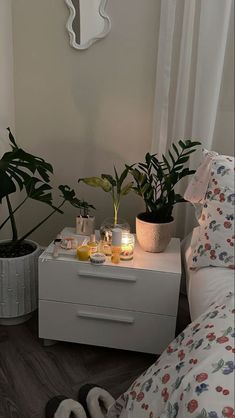 a bedroom with plants and candles on the nightstand