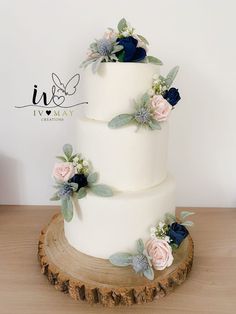 a three tiered wedding cake with flowers on it sitting on top of a tree stump